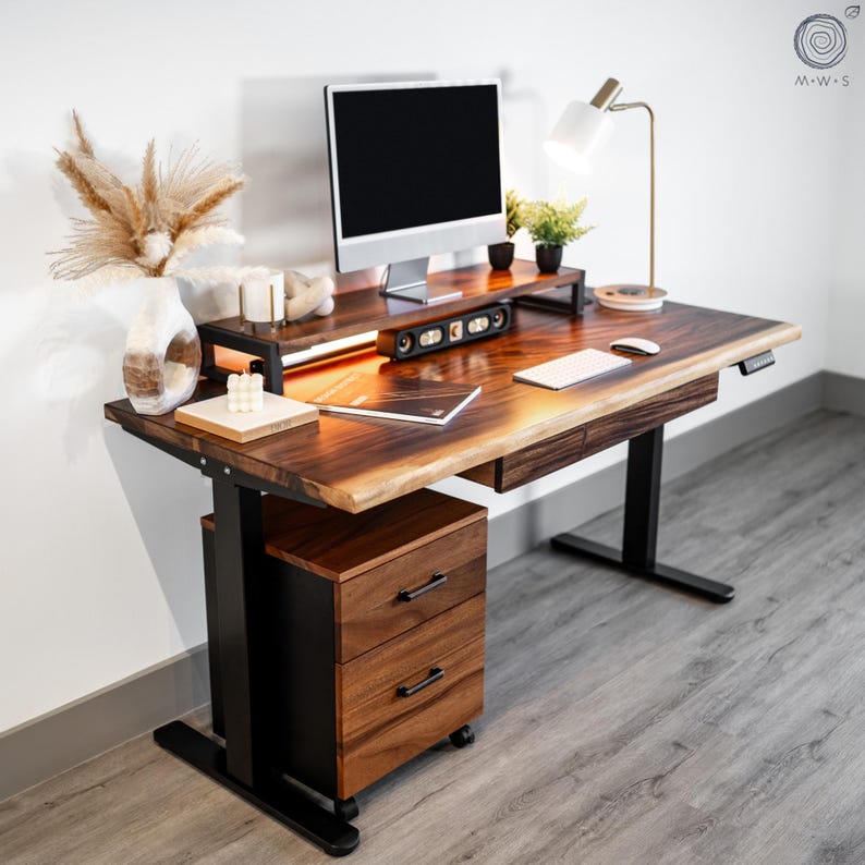 May include: Walnut monitor stand on a live edge walnut standing desk, styled with a monitor, desk lamp, keyboard, and matching file cabinet in a modern home office setup.