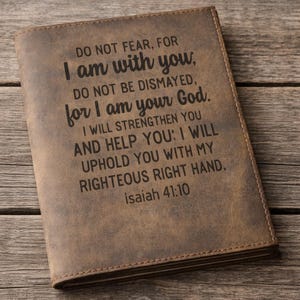 May include: A brown leather journal cover featuring the engraved text: DO NOT FEAR, FOR I am with you, DO NOT BE DISMAYED, for I am your God. I WILL STRENGTHEN YOU AND HELP YOU: I WILL UPHOLD YOU WITH MY RIGHTEOUS RIGHT HAND. isaiah 41:10.