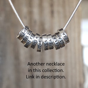 Sterling silver mother's necklace with tiny rings stamped with kids names on a snake chain.