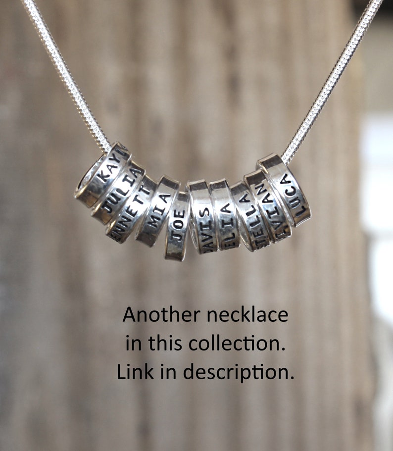 Sterling silver mother's necklace with tiny rings stamped with kids names on a snake chain.