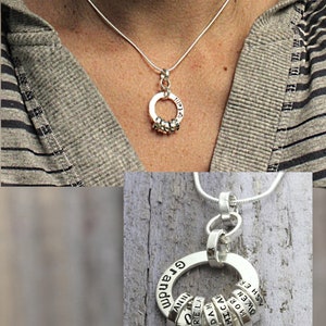 Sterling silver necklace for Grandmother with tiny rings stamped with grandkids names, around a washer around a woman's neck.