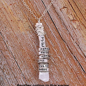Sterling silver mother's necklace with tiny silver name rings wrapped around a vertical bar stamped with a word.