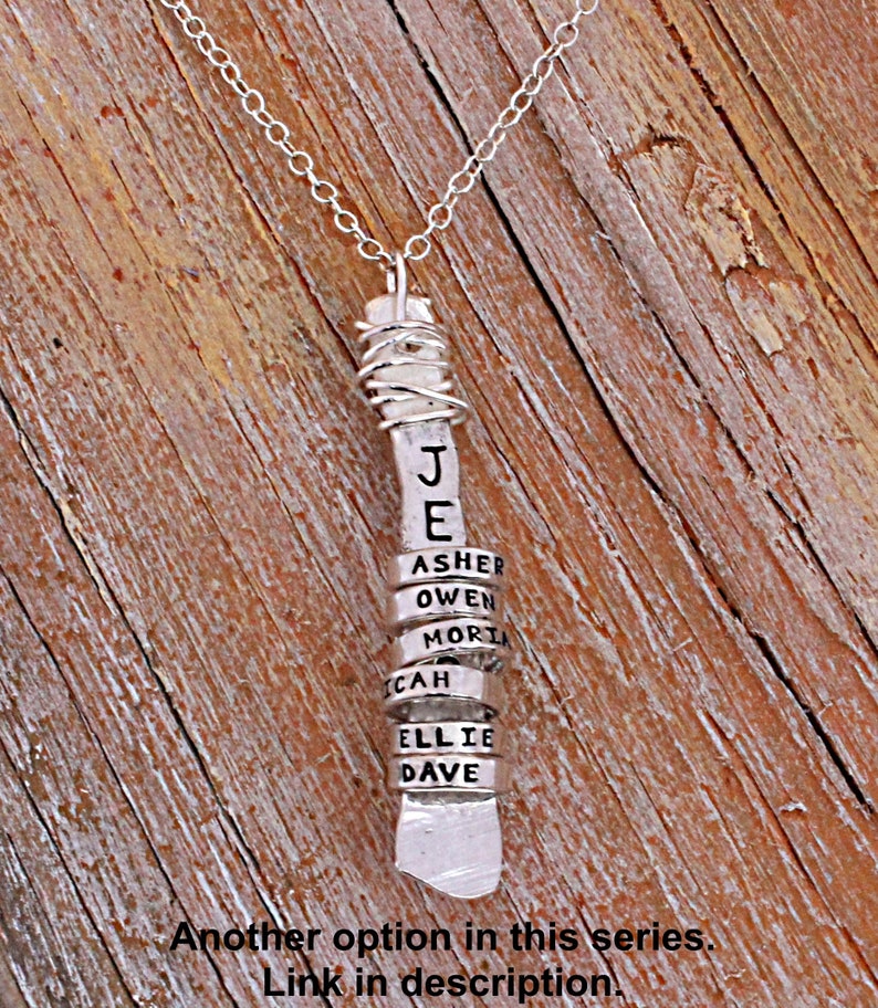 Sterling silver mother's necklace with tiny silver name rings wrapped around a vertical bar stamped with a word.
