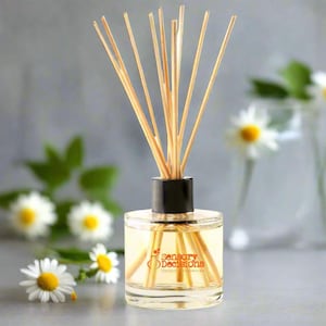 Op de afbeelding: Een heldere glazen diffuserfles met een zwarte dop en houten stokjes. De fles bevat een lichtgele vloeistof en heeft een etiket met de tekst "Sensory Decisions Unique Fragrances".
