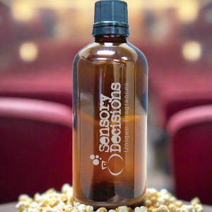 Könnte beinhalten: Eine braune Glasflasche mit schwarzem Deckel und dem Text "sensory decisions unique fragrances" auf der Seite. Die Flasche steht auf einem Haufen Popcorn.