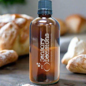 May include: A brown glass bottle with a black lid and a white label that says "Sensory Decisions. Unique. Fragrances." The bottle is sitting on a wooden surface with a small pile of white powder in front of it.