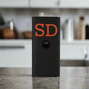 May include: A black rectangular box with a round button and the letters "SD" in orange on the front.