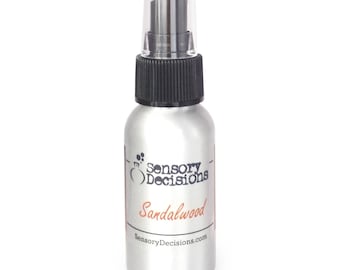 May include: A silver spray bottle with a black cap and a white label that says "Sensory Decisions" and "Sandalwood". The label also includes the website address "SensoryDecisions.com".