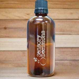 Puede incluir: Una botella de vidrio marrón con una tapa negra. La botella está etiquetada con "Sensory Decisions, Unique Fragrances".