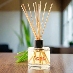 Puede incluir: Un difusor de vidrio transparente con tapa negra y palitos de madera. La botella contiene un líquido amarillo claro y tiene el texto "Sensory Decisions Unique Fragrances" impreso en la etiqueta.