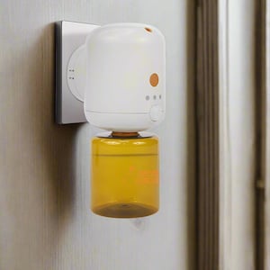 Puede incluir: Un difusor de aceites esenciales blanco y naranja enchufado a una toma de corriente. El difusor tiene un diseño cilíndrico con un depósito de aceite transparente de color ámbar. El dispositivo tiene un botón y luces indicadoras.