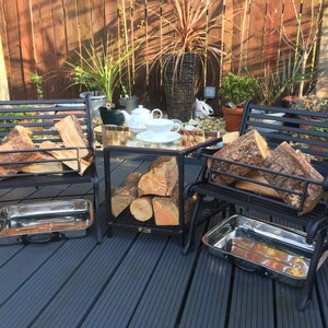 May include: Two black metal benches with wood storage compartments and metal trays. The benches are on a black composite deck with a glass-top table in the centre. The table has a teapot and teacups on it.