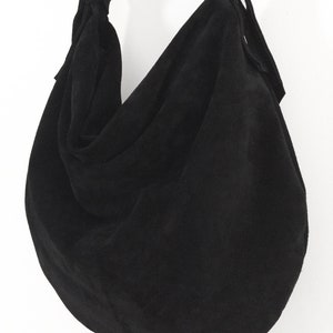 May include: A black suede hobo bag with a knotted strap and a slouchy design.