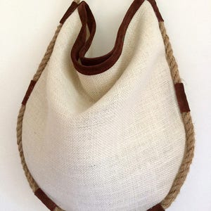 Peut inclure: Un sac cabas en toile blanche avec une bordure en daim marron et une &eacute;paisse poign&eacute;e en corde.