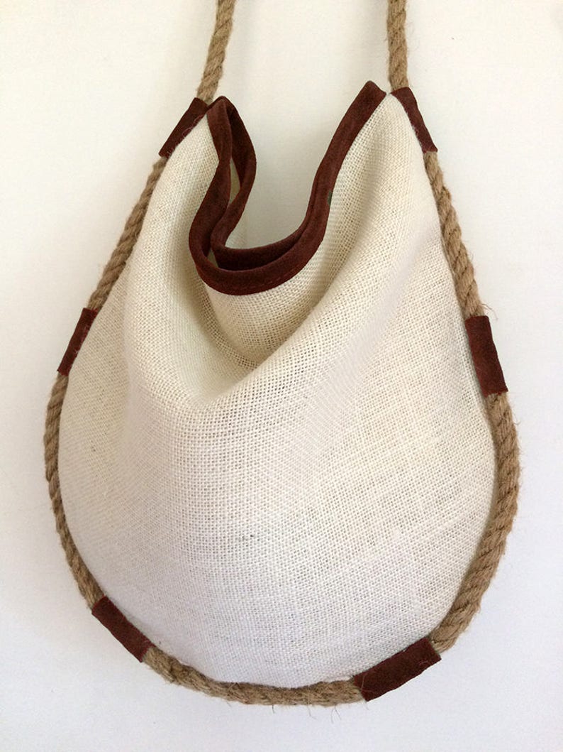 Peut inclure: Un sac cabas en toile blanche avec une bordure en daim marron et une &eacute;paisse poign&eacute;e en corde.