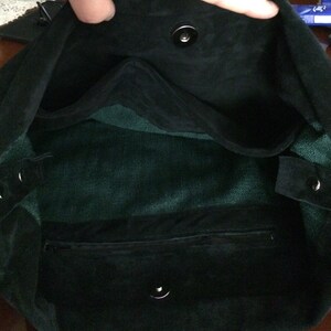 May include: Black suede tote bag with a green fabric lining and a zipped pocket. The bag has two snap closures.