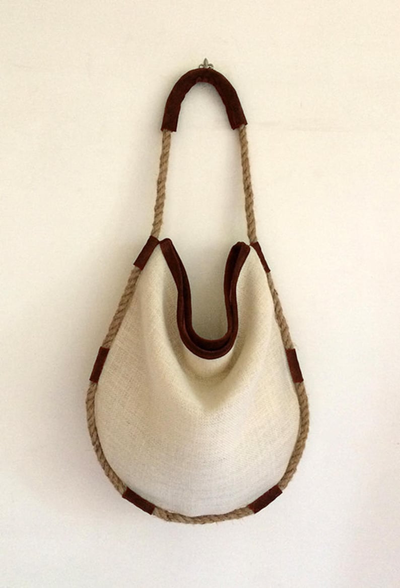 Peut inclure: Un sac fourre-tout en toile blanche avec des finitions en cuir marron et des anses en corde.
