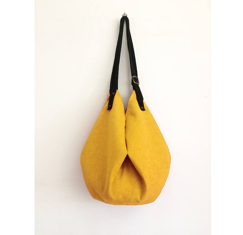May include: A yellow canvas tote bag with black leather straps and a buckle closure.