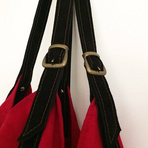 May include: Red tote bag with black leather straps and brass buckles.