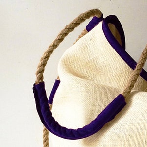 Peut inclure: Un sac fourre-tout en fibre naturelle avec une bordure violette et des anses en corde.