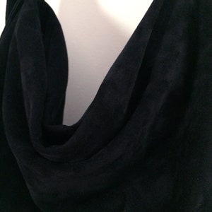 May include: A close-up of a black suede fabric with a soft, drapey texture.