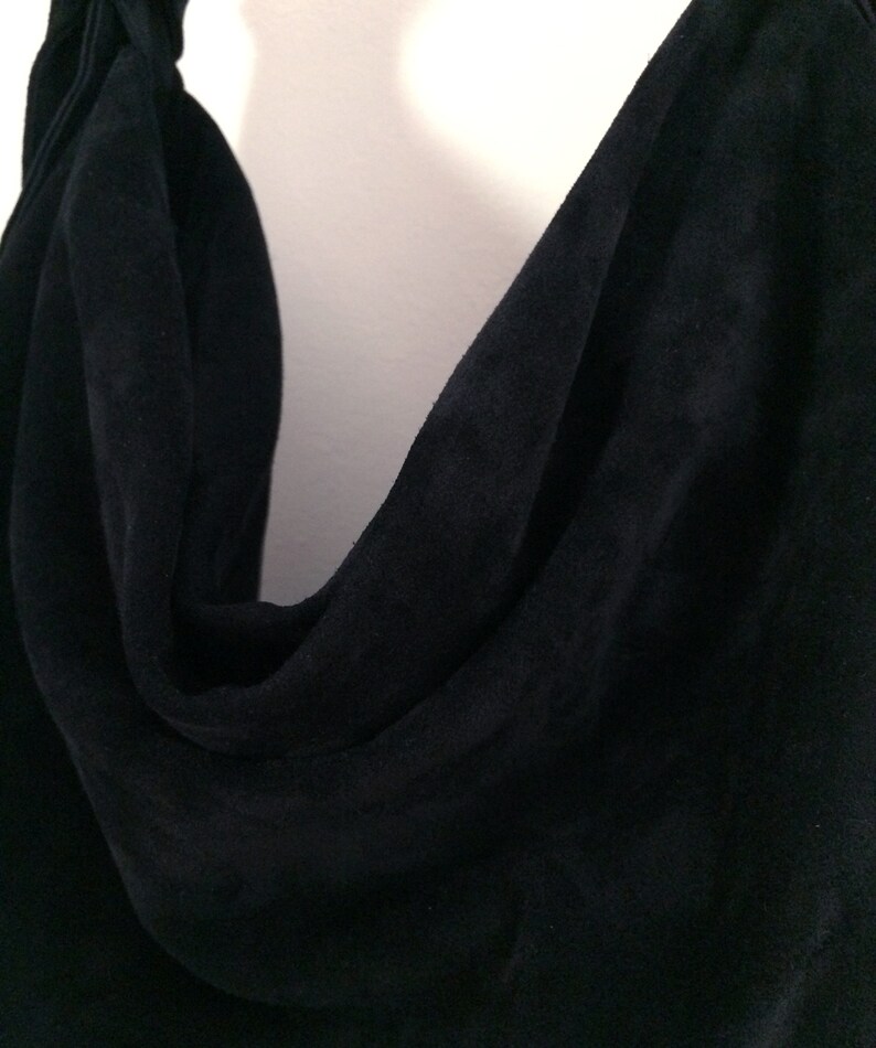 May include: A close-up of a black suede fabric with a soft, drapey texture.