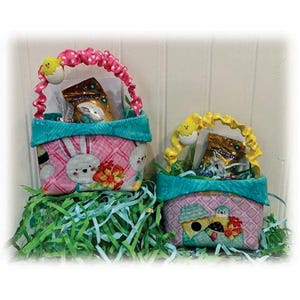 May include: Two small fabric Easter baskets with handles. The pink basket has a bunny and floral print and the other basket has a birdhouse and floral print. Both baskets are filled with candy and small toys.