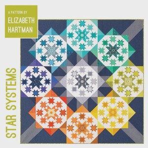 May include: A patchwork quilt design named "Star Systems" by Elizabeth Hartman. The quilt showcases a repeating star pattern in shades of blue, green, orange, and yellow, set against a dark blue backdrop. The text "A Pattern By Elizabeth Hartman" is in a green box.