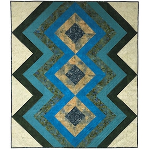 May include: A quilt featuring a geometric pattern of blue, green and beige squares. The squares are arranged in a symmetrical pattern, creating a visually appealing design.