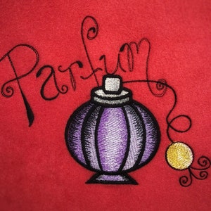 May include: Embroidered design of a purple perfume bottle with a gold cap and a yellow drop of perfume. The word "Perfume" is written in a cursive font above the bottle.