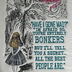 Op de afbeelding: Geborduurde afbeelding van Alice uit Alice in Wonderland die in een bos staat met een Cheshire Cat in een boom erboven. De tekst luidt "Ben ik gek geworden?" "Ik vrees van wel, je bent helemaal gek, maar ik zal je een geheim vertellen... de beste mensen zijn zo."