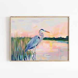 May include: A painting of a blue heron standing in a marsh at sunset. The heron is facing right and has its head turned to the left. The water is a light blue and pink color, and the sky is a light pink and purple color.