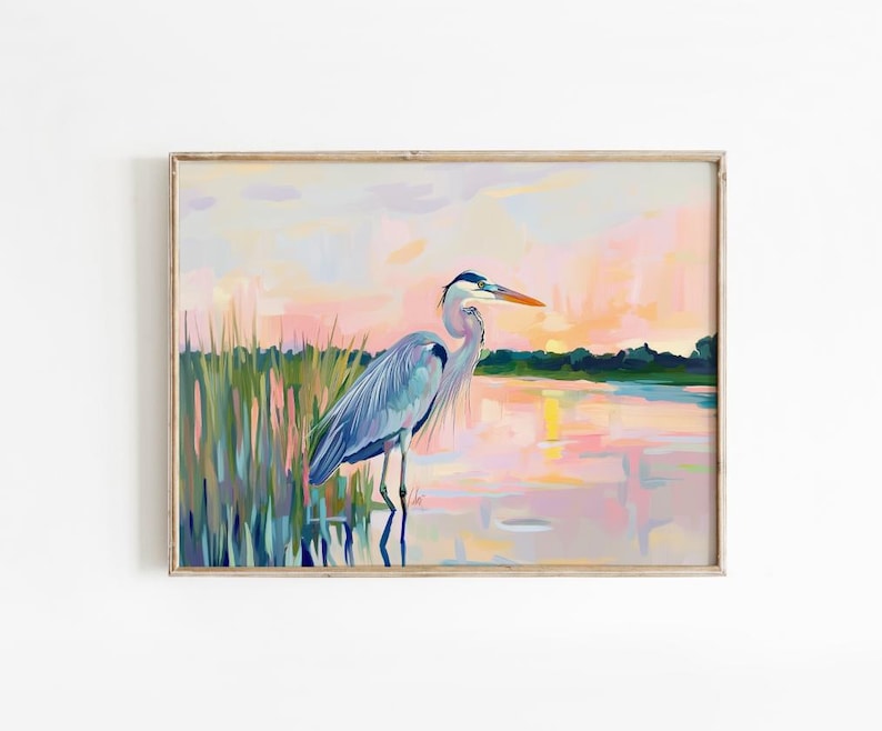 May include: A painting of a blue heron standing in a marsh at sunset. The heron is facing right and has its head turned to the left. The water is a light blue and pink color, and the sky is a light pink and purple color.
