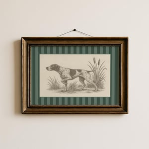 May include: A framed print depicting a Pointer dog in a field, rendered in sepia tones. The artwork is set against a green and white striped background, within a dark wood frame. The print is suspended on a white wall.