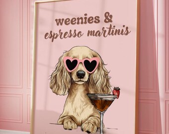 May include: A pink and gold framed print with a cartoon dachshund wearing pink heart-shaped sunglasses and holding a martini glass with a strawberry garnish. The text on the print reads "weenies & espresso martinis".