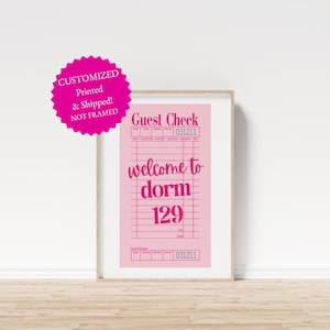 Puede incluir: Una impresión rosa enmarcada con las palabras "Guest Check" y "welcome to dorm 129". La impresión tiene un patrón de cuadrícula y el texto "CUSTOMIZED Printed & Shipped! NOT FRAMED" en un círculo rosa.