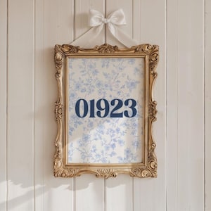 Może przedstawiać: Oprawiony wydruk ze złotą, ozdobną ramą, zawieszony na białej kokardzie. Wydruk przedstawia jasnoniebieski wzór kwiatowy na kremowym tle, z granatowym numerem "01923".