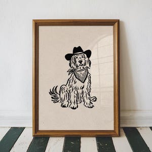 Könnte beinhalten: Ein gerahmter Druck mit einer Schwarz-Weiß-Illustration eines Hundes mit Cowboyhut und Halstuch. Der Hund sitzt. Der Rahmen hat eine warme braune Farbe.
