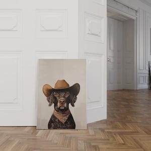 以下が含まれることがあります： 茶色と黒の犬が茶色のカウボーイハットをかぶり、首に茶色のバンダナをしています。犬はカメラを見つめています。