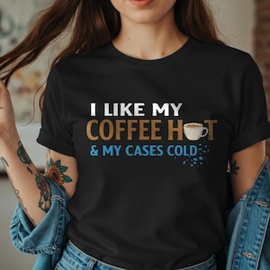 May include: A black t-shirt with white text that reads "I like my coffee hot & my cases cold". A small image of a coffee cup with steam is above the text.