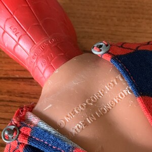 K&ouml;nnte beinhalten: Vintage Spider-Man-Actionfigur mit rotem und blauem Kost&uuml;m mit Spinnennetz-Muster. Der Kopf der Figur ist rot, der K&ouml;rper ist hautfarben. Der Text auf der Figur lautet: "MEGO CORP. 1977 MADE IN HONGKONG".