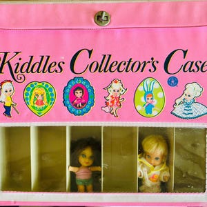May include: A vintage pink Kiddle's Collector's Case with the text "Kiddles Collector's Case" in black script. The case features several colorful Kiddle doll stickers and a clear compartment holding two dolls. The case has a silver clasp.