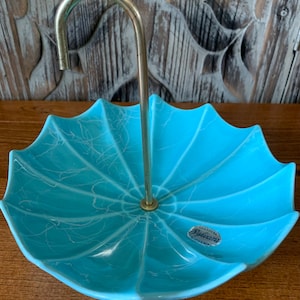 May include: A blue ceramic umbrella-shaped dish with a gold metal stand. The dish has a white crackle glaze and a label that reads "Sylvan" Pasadena, California."