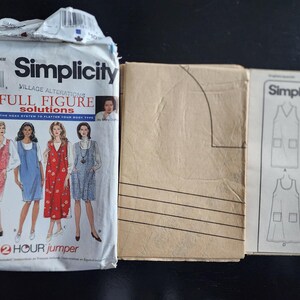 May include: A Simplicity 7162 sewing pattern envelope for a full figure jumper, featuring illustrations of four variations of the garment. Beside it are folded brown paper pattern pieces and an instruction sheet showing line drawings of the designs.