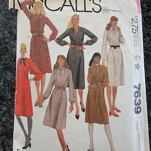 Könnte beinhalten: Ein McCall's 7639 Schnittmusterumschlag mit Illustrationen von fünf verschiedenen Kleiderstilen mit langen Ärmeln, verschiedenen Ausschnitten und gegürteten Taillen. Der weiße Papierumschlag zeigt den Markennamen, die Nummer und Größen.