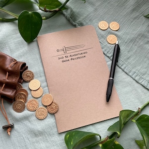 May include: A brown notebook with a sword illustration and the text "D+D 5E ADVENTURING GEAR PRICEBOOK". The notebook is surrounded by gold coins and a green plant.