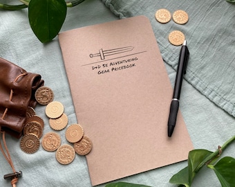 May include: A brown notebook with a sword illustration and the text "D+D 5E ADVENTURING GEAR PRICEBOOK". The notebook is surrounded by gold coins and a green plant.