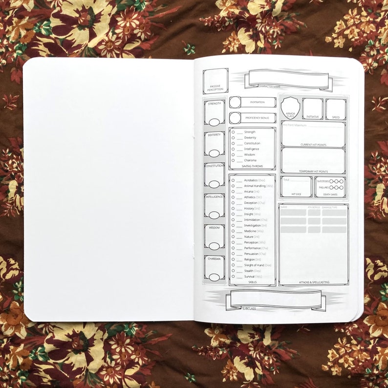 May include: Open notebook with character sheet pages. The pages have black and white printed templates for role-playing games. The notebook is open on a brown floral patterned surface.