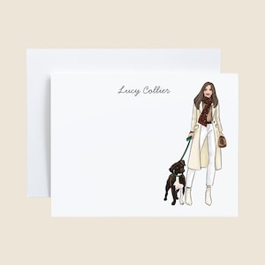 May include: White stationery set featuring an illustration of a person in a cream-colored coat, white pants, and boots, walking a black and brown dog on a green leash. The text "Lucy Collier" is written in black script.