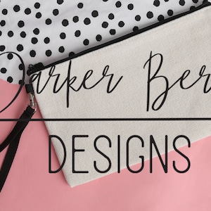 May include: A white canvas zippered pouch with a black zipper and a black strap. The pouch has the text "Parker Berry Designs" printed on it in black.